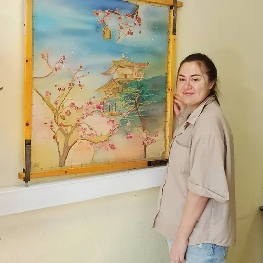 Женщина стоит рядом с картиной японского храма и цветущими вишнями в уютном помещении