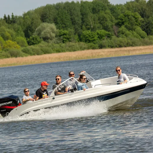 Группа людей на скоростном катере, наслаждающихся летом на реке среди зелени и природы