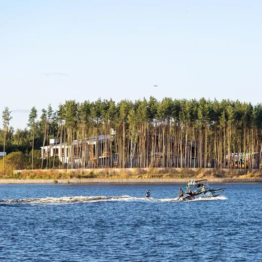 На реке человек управляет лодкой рядом с лесом в солнечный день