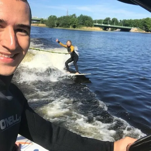 Молодой человек и девушка занимаются вейкбордингом на реке в солнечный день