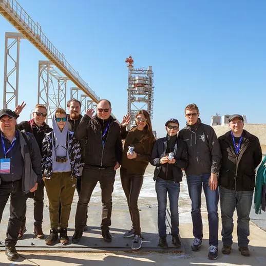 Группа людей на площадке космодрома во время экскурсии в ясный солнечный день