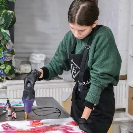 Молодая художница работает над абстрактной картиной с помощью фена для создания эффектов