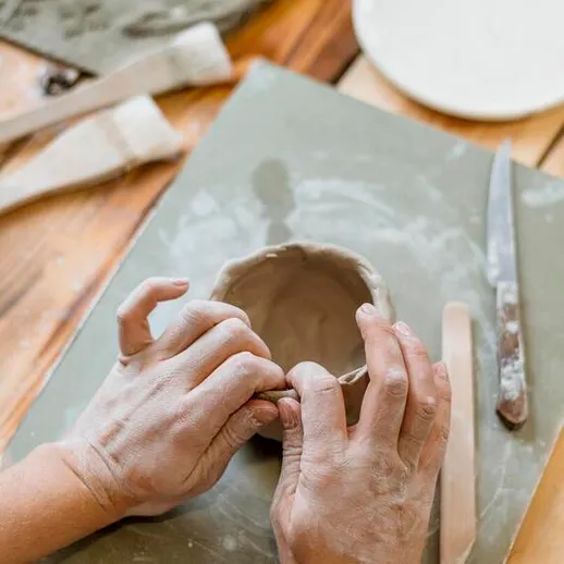 Работа с глиной в студии керамики на деревянном столе в дневное время