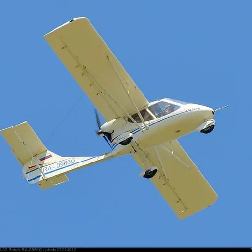 Малый одномоторный самолет на фоне ясного синего неба в летний день, совершает полет над открытой местностью