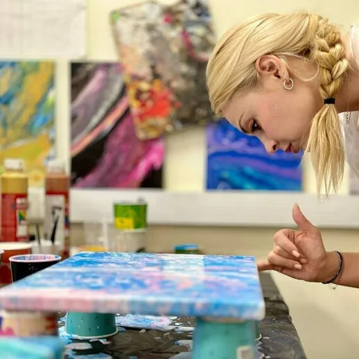 Молодая женщина создает абстрактную картину в творческой студии в дневное время