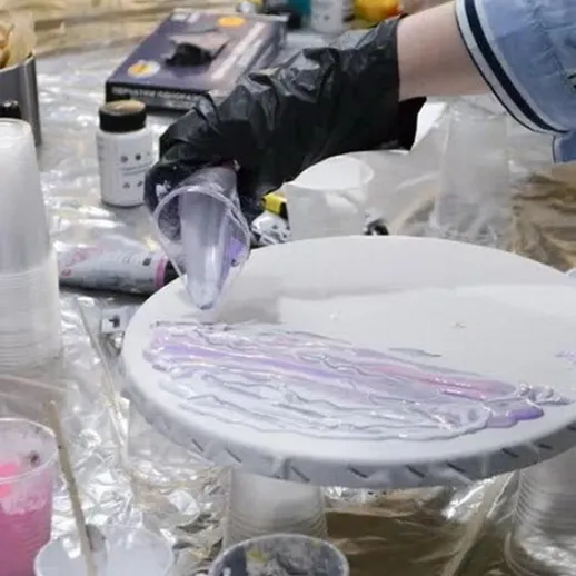 Процесс создания акриловой росписи на круглом холсте в творческой студии с использованием различных красок