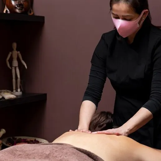 Массажист проводит расслабляющий массаж спины клиенту в спа-салоне во время вечерней процедуры