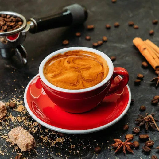 Ароматный кофе в красной чашке на столе с корицей и сахаром в кафе, осеннее утро