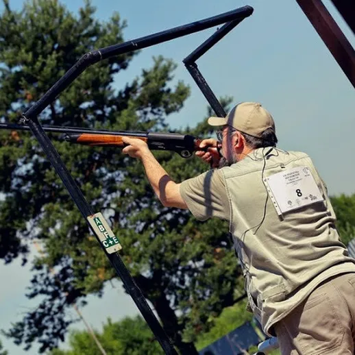 Стрелок целится в мишень на соревнованиях по стендовой стрельбе на открытом воздухе в летний день