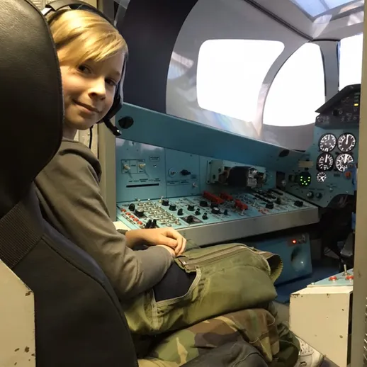 Мальчик в пилотской кабине самолета, осматривающий приборы и оборудование во время экскурсии