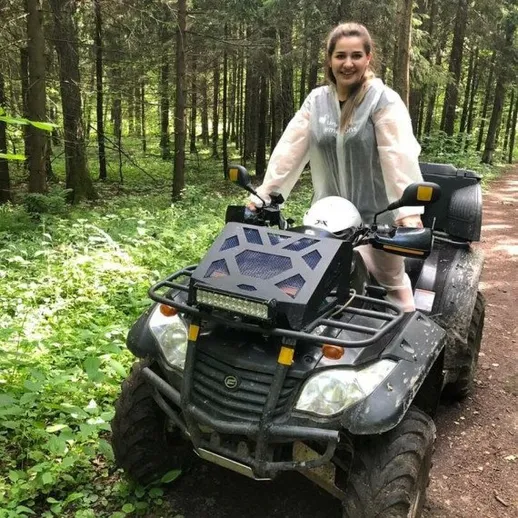 Молодая женщина на квадроцикле едет по лесной тропинке солнечным днем в России