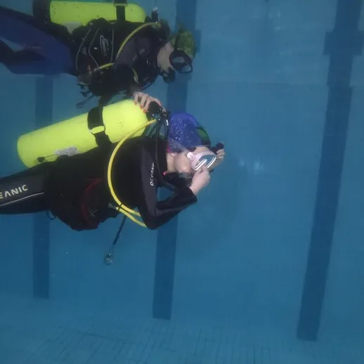 Подводное плавание в бассейне с аквалангом, два дайвера исследуют водное пространство в ясный день