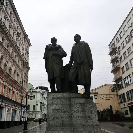 Скульптуры двух исторических деятелей на улице в центре города в пасмурный день