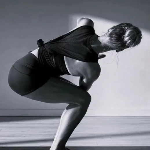 Практика йоги в студии, женщина выполняет сложную асану на полу в утреннем освещении