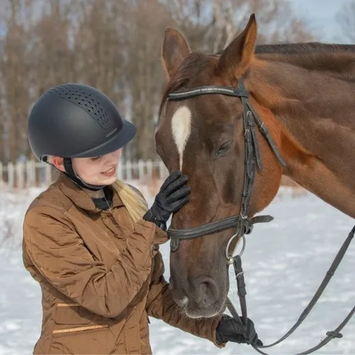 Девушка гладит лошадь в зимнем пейзаже на фоне леса и снега