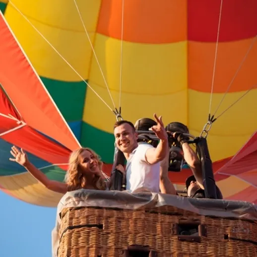 Пара наслаждается полетом на воздушном шаре над городом в ясный день