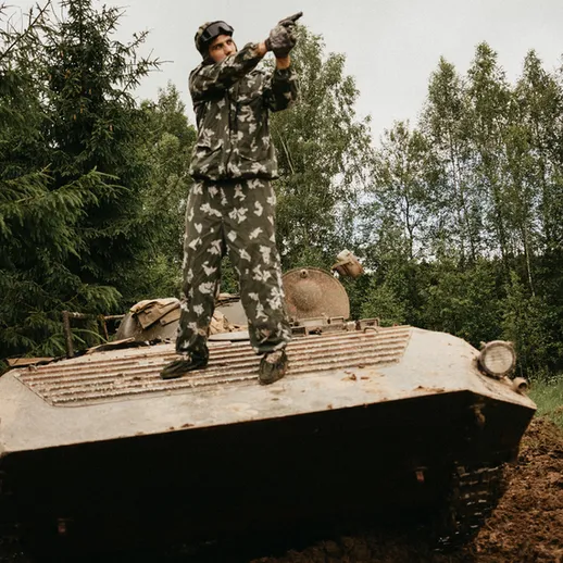 Военный солдат в камуфляжной форме стреляет с бронетранспортера в лесной местности