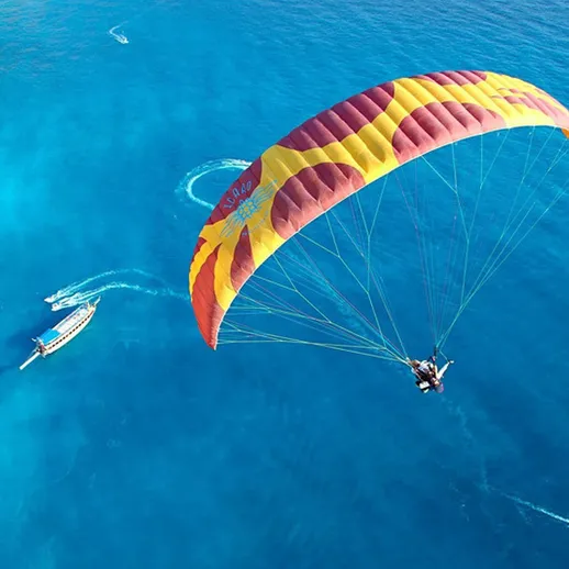 Парапланеризм над кристально чистым морем с лодками под солнцем в тропическом раю