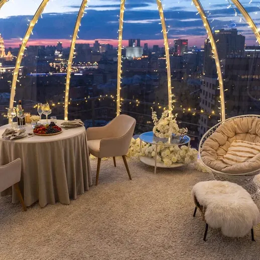 Уютное романтическое место для ужина с видом на ночной город и украшением из огней