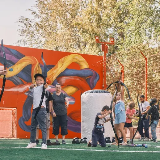 Участники соревнований по стрельбе из лука на спортивной площадке в парке