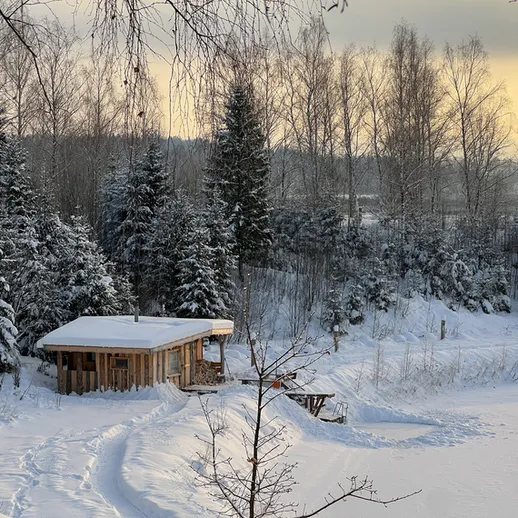 Снежный пейзаж с деревянным домиком у замерзшего озера в зимний вечер