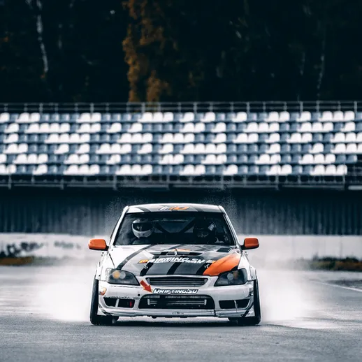 Мощный дрифт на спортивном автомобиле на гоночном треке в осенний день