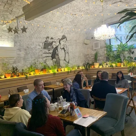 Вечерняя встреча друзей в уютном кафе с зелеными растениями и красивым освещением в центре города