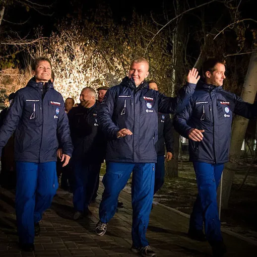 Команда спортсменов в синей форме приветствует зрителей в зимнем вечернем парке