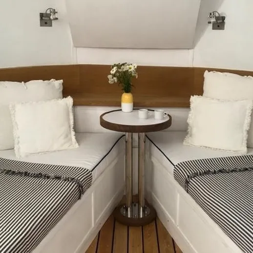 Уютный уголок на яхте с белыми подушками и цветами на столике, расположенный в салоне