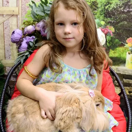 Девочка с кроликом на зеленом фоне в саду, солнечный день и радостная атмосфера