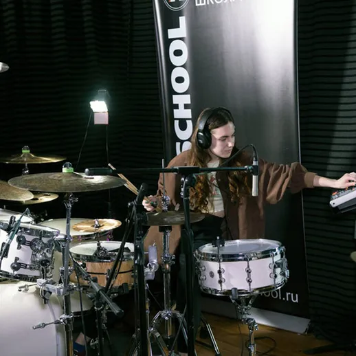 Музыкант играет на ударных в студии, создавая уникальные звуки с помощью электронного оборудования