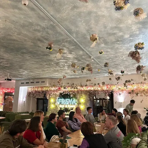 Люди обсуждают идеи в уютном кафе с красивым интерьером и цветами на потолке в ноябре