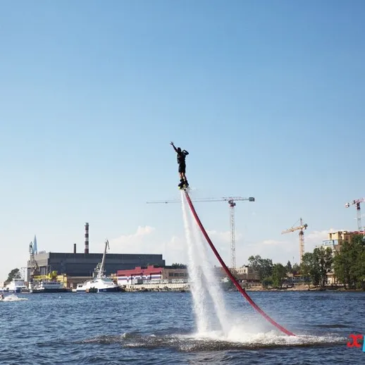 Соревнующийся водный акробат демонстрирует трюки на устройстве для водного полета на реке в солнечный день
