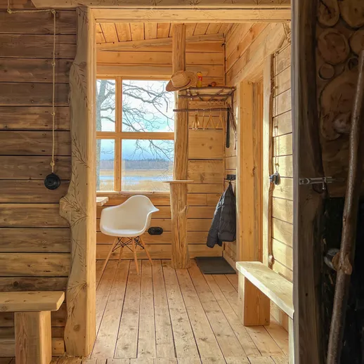 Уютный деревянный интерьер загородного дома с большой окном и простыми мебели