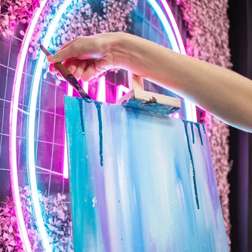 Художник создает абстрактную картину в ярком арт-пространстве с неоновыми огнями