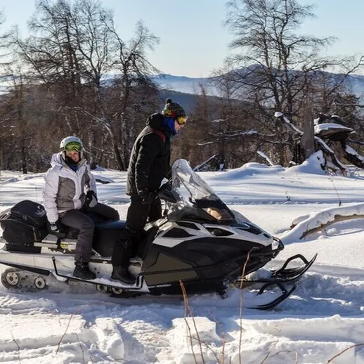 Зимняя прогулка на снегоходе по снежным просторам в горах