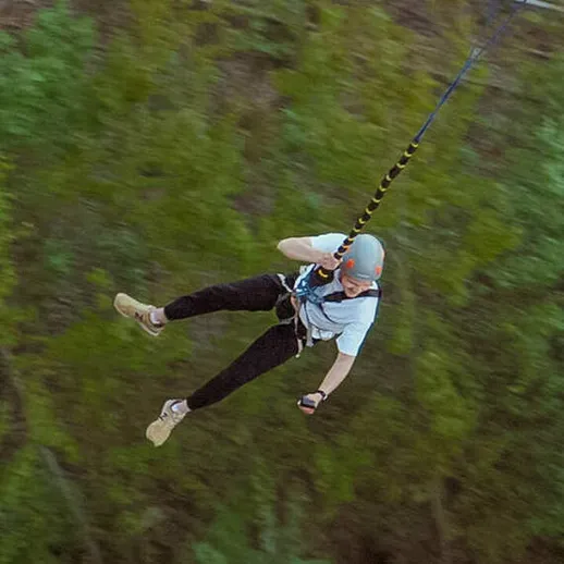 Мужчина на зиплайне в лесу, наслаждающийся скоростью и природой в солнечный день