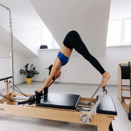 Женщина выполняет упражнения на гимнастическом аппарате в светлом зале в спортивной студии