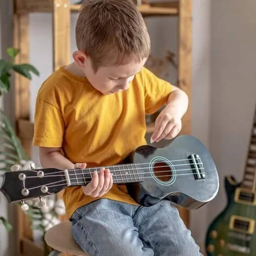 Мальчик играет на укулеле в уютной комнате