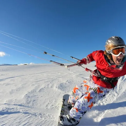 Кайтсерфер на фоне снежных гор в ярком зимнем наряде с восторженным выражением лица