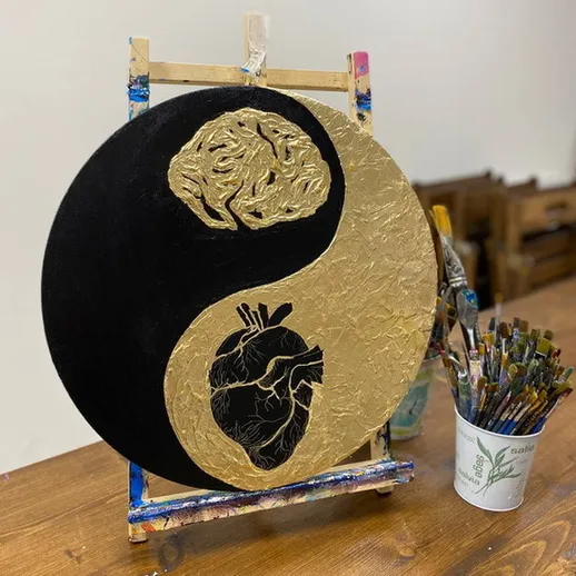 Изображение золотого символа инь-янь с мозгом и сердцем на черном и золотом фоне в художественной студии