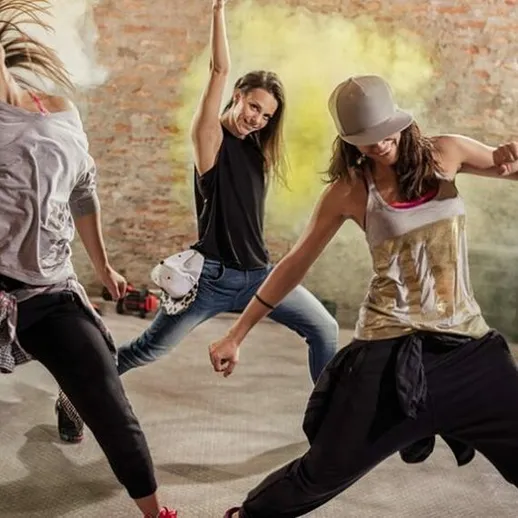 Танцевальная группа выполняет энергичный хип-хоп в студии, наполненной ярким светом и динамикой