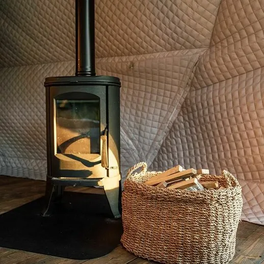 Уютный уголок с деревянной печкой и корзиной дров в загородном доме на спокойном вечере
