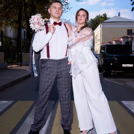 Молодожены на улице в свадебных нарядах во время проведения фотосессии в центре города