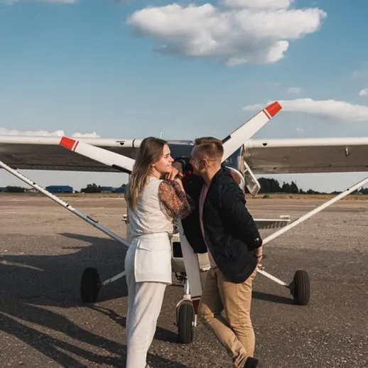 Молодая пара на аэродроме перед легким самолетом в солнечный день