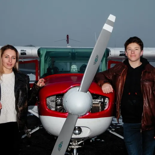 Два человека возле самолета на зимнем фоне, готовясь к полету на тренировку в холодный зимний день в России