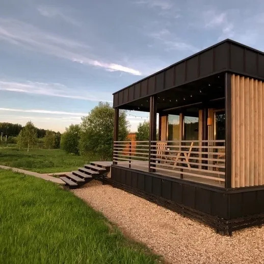 Современный домик на природе с большим окном и деревянной террасой в ясный день