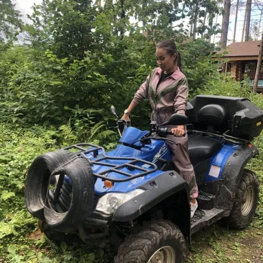 Женщина на квадроцикле в лесу летом