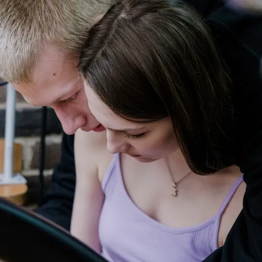 Молодая пара нежно общается, сидя рядом, и погружена в творческий процесс на открытом воздухе