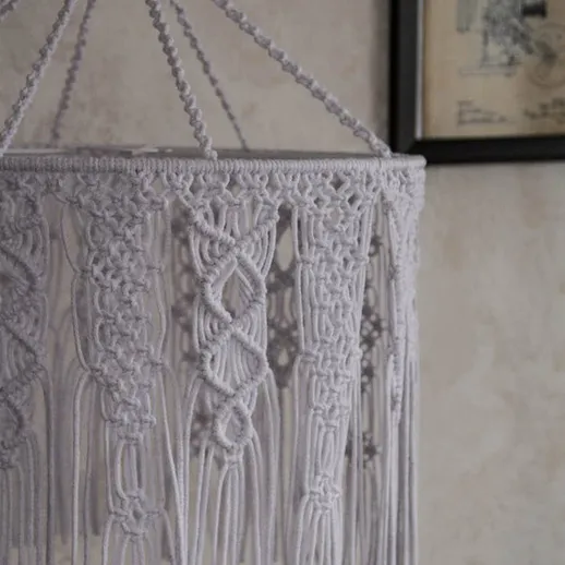 Декоративный светильник из макраме с оригинальным узором, повешенный на стене в уютном интерьере